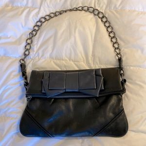 Black leather bag with fold over blue leather bow.